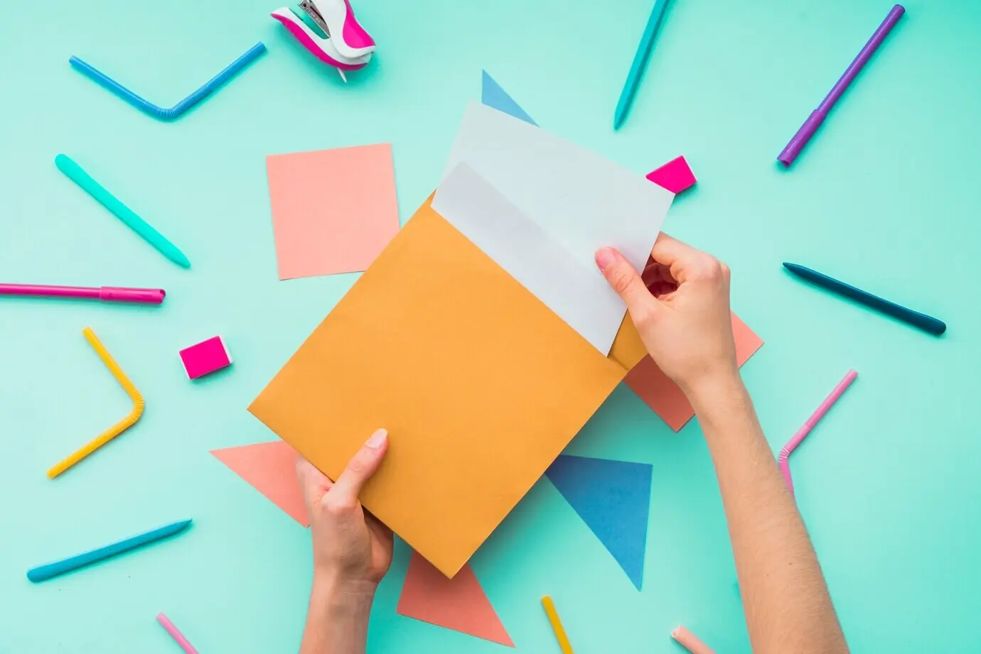 Eine weibliche Hand nimmt über den Schreibutensilien eine Karte aus einem Umschlag.